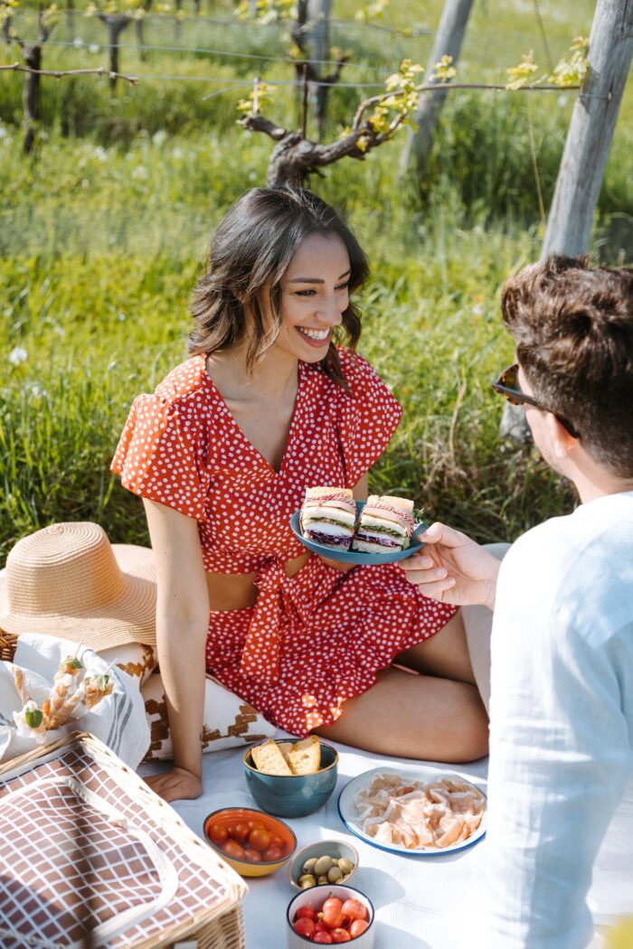 donna che sorride seduta su un prato durante un pic nic